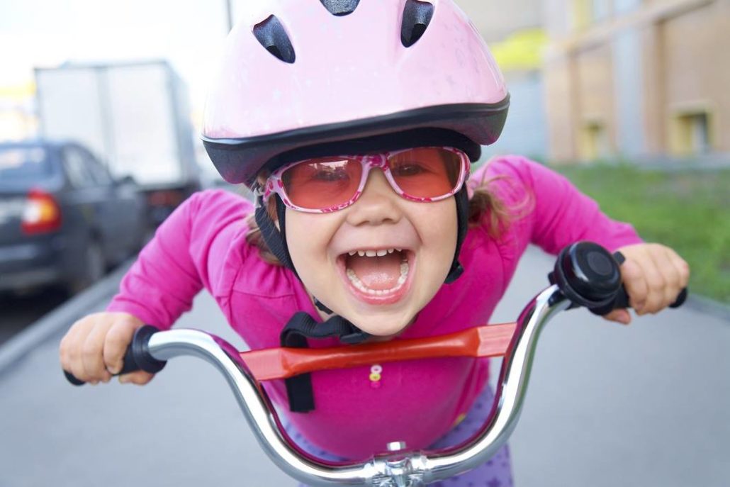 טיפים לרכיבה על אופניים עם משקפיים. ילדה עם משקפיים רוכבת על אופניים