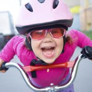 ילדה עם משקפיים רוכבת על אופניים